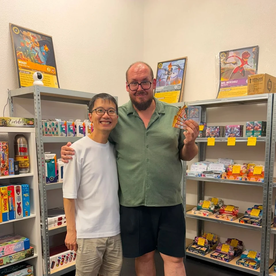 Two players posing with trading cards in the store