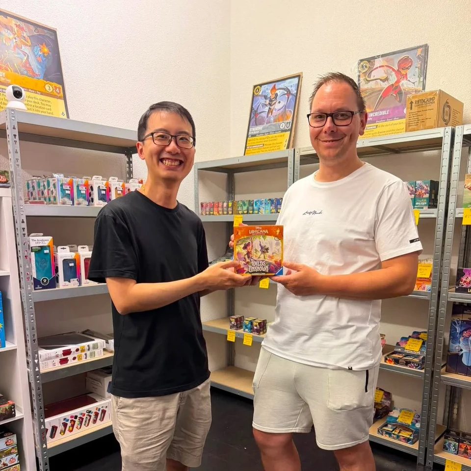 Two players posing with a trading card in the store